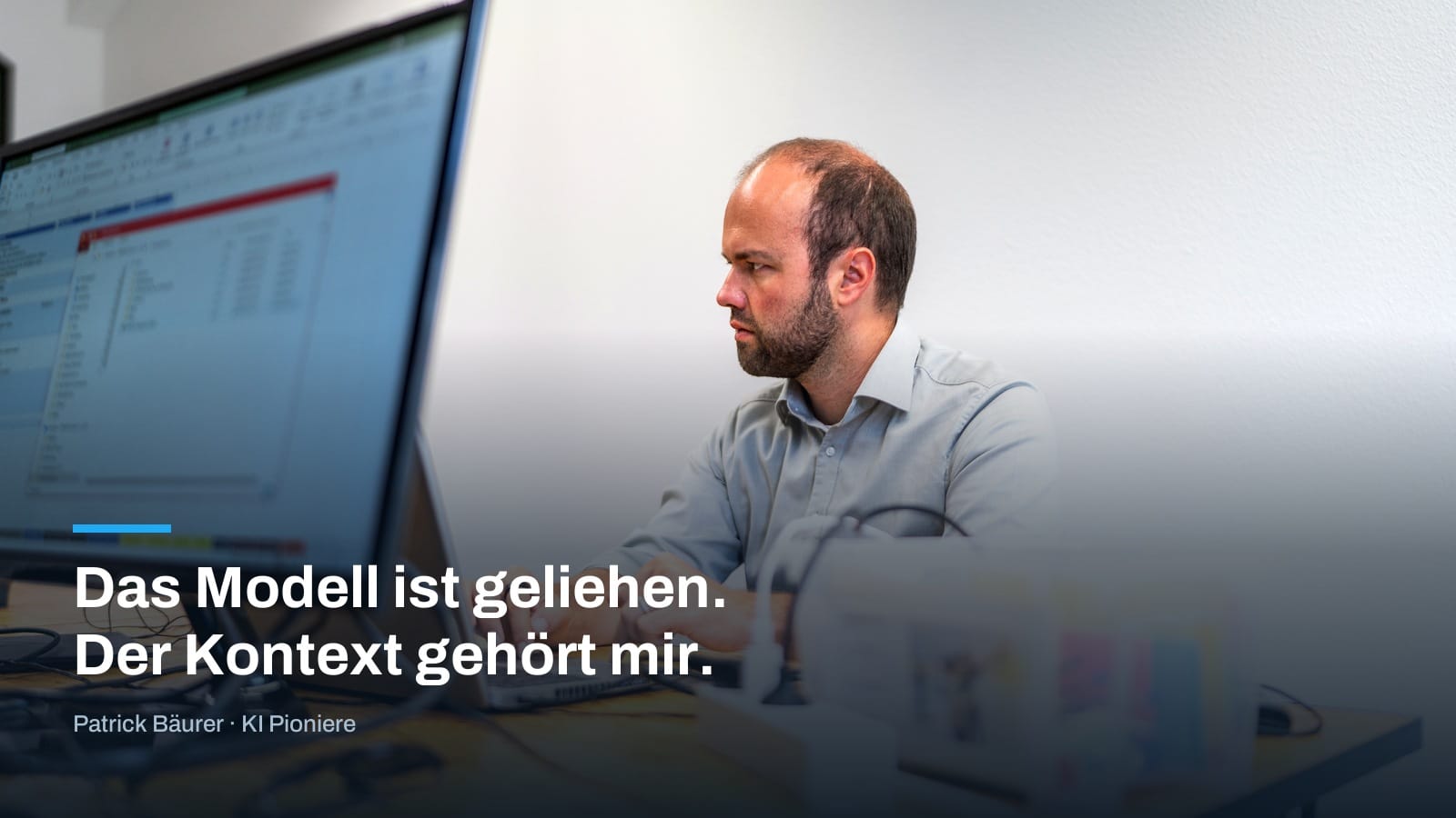 Patrick Bäurer am Rechner, darüber das Bildzitat „Das Modell ist geliehen. Der Kontext gehört mir.“